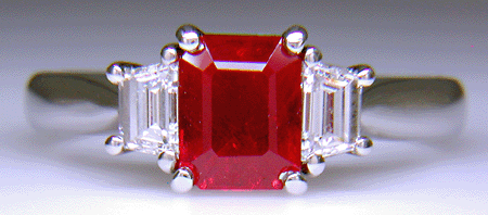 A fiery red ruby set with two trapezoid-cut diamonds in a hand-crafted platinum ring. (J6405)