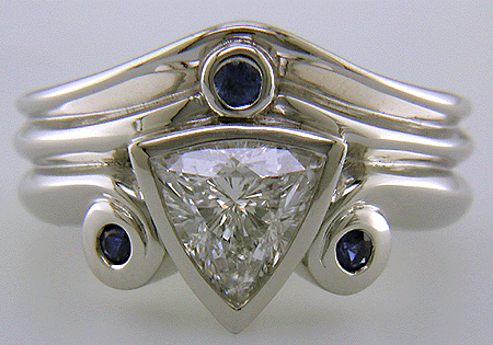 A trilliant diamond ring with three small sapphires.