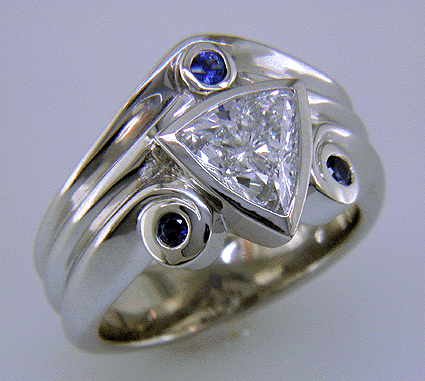A trilliant diamond ring with three small sapphires.