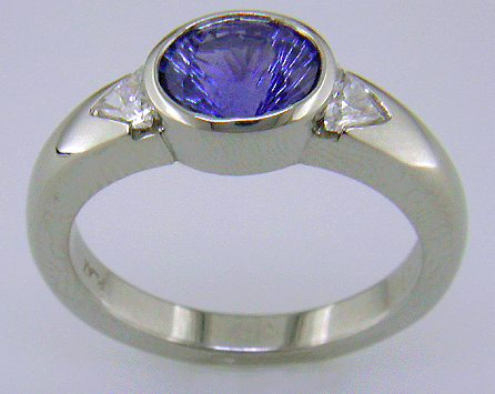 Side view of concave-faceted sapphire and trilliant diamonds in a custom platinum ring.