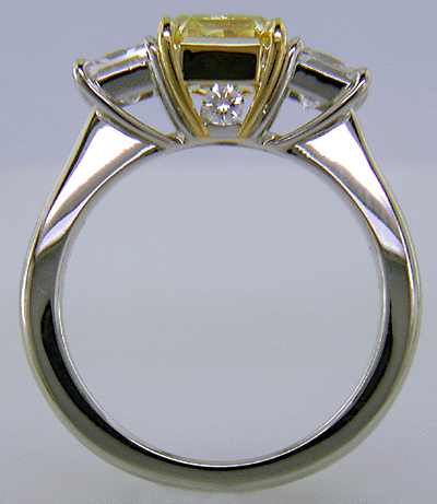 Fancy Intense Yellow diamond set with two radiant-cut diamonds in a custom platinum ring.