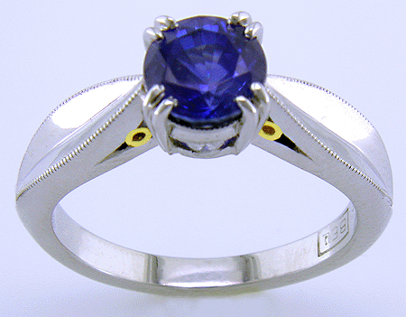 Platinum sapphire ring with two hidden diamonds and 18kt gold accents.