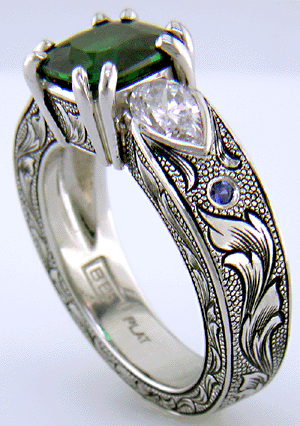 A cushion-cut Tsavorite garnet set in a beautifully hand crafted and engraved platinum ring.