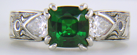 A cushion-cut Tsavorite garnet set in a beautifully hand crafted and engraved platinum ring.