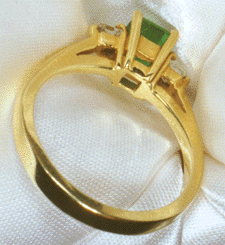 Inside-view of 18kt gold ring with an emerald and princess cut diamonds.