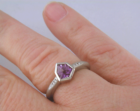 Alpine-cut purple sapphire with round diamonds in a custom platinum ring.