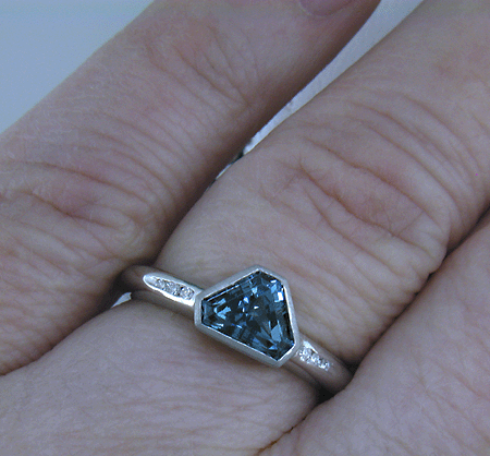 Alpine-cut purple sapphire with round diamonds in a custom platinum ring.