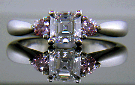 An Asscher-cut diamond set with two Fancy Intense Pink diamonds in a handcrafted platinum ring.