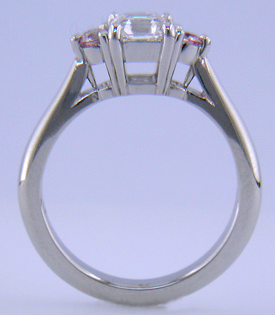 Side view of an Asscher-cut diamond set with two Fancy Intense Pink diamonds in a handcrafted platinum ring.