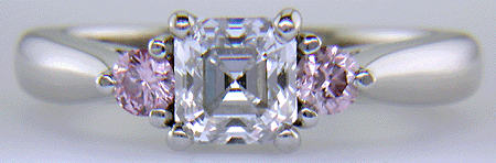 Hand-crafted platinum ring with an Asscher-cut diamond and two Fancy Intense Pink diamonds.