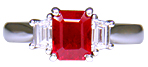 A fiery red ruby set with two trapezoid-cut diamonds in a handcrafted platinum ring.