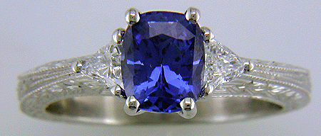 Hand engraved platinum ring withcushion-cut sapphire and trilliant diamonds.