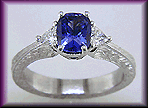 Cushion-cut sapphire and trilliant diamond hand-engraved platinum ring.