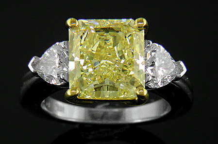Yellow radiant-cut diamond with heart-shape diamonds in a custom platinum ring.