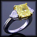 Yellow radiant-cut diamond with heart-shape diamonds in a custom platinum ring.
