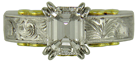Hand-engraved platinum and gold engagement ring with an emerald cut diamond.