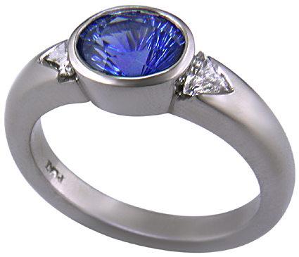 Concave-faceted sapphire and trilliant diamonds in a custom platinum ring.