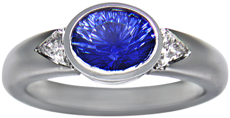 Concave-faceted sapphire and trilliant diamonds in a custom platinum ring.