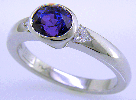 Oval sapphire ring with trilliant diamonds crafted in platinum.