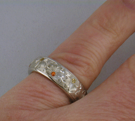 Hand engraved platinum band set with mandarin garnets.