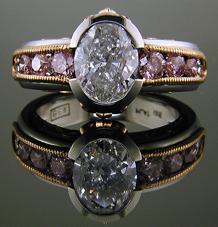 Oval diamond set with 6 brilliant pink diamonds in a custom rose gold and platinum ring.