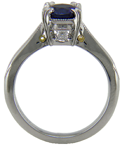 Side view of sapphire ring with two hidden diamonds and 18kt gold accents.