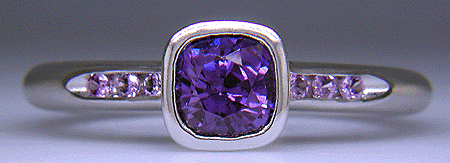 Cushion-cut purple sapphire set with round lilac sapphires in a custom platinum ring.