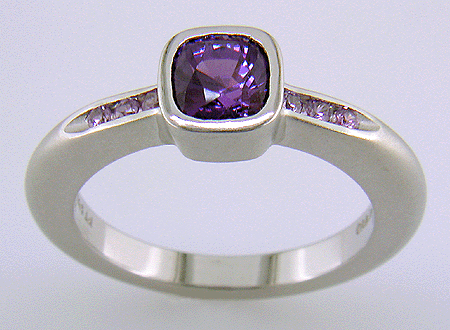 Side view of purple sapphire set with round lilac sapphires in a custom platinum ring.