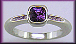 Cushion-cut purple sapphire with round lilac sapphires in a custom platinum ring.