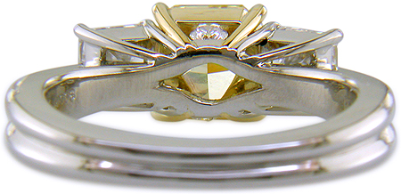 Inside view of custom platinum ring with yellow diamond set with two radiant-cut diamonds.