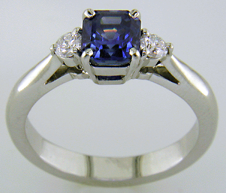 Side view of barion-cut sapphire set with two round diamonds in a handcrafted platinum ring.
