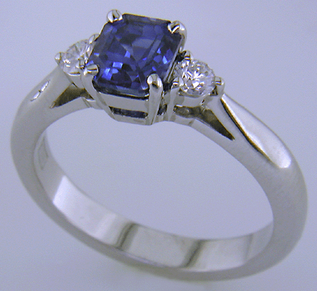 Emerald-cut sapphire set with two round diamonds in a handcrafted platinum ring.