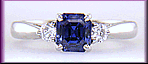 Emerald-cut sapphire set with two round diamonds in a handcrafted platinum ring.