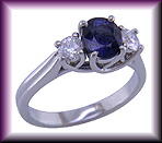 Platinum trellis ring set with an oval sapphire and two diamonds.