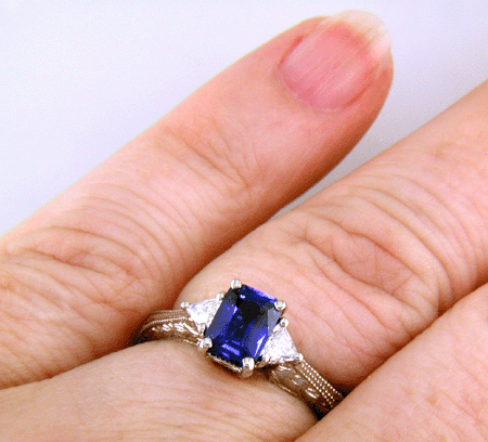 Sapphire ring with trilliant diamond and hand engraved platinum on the hand.