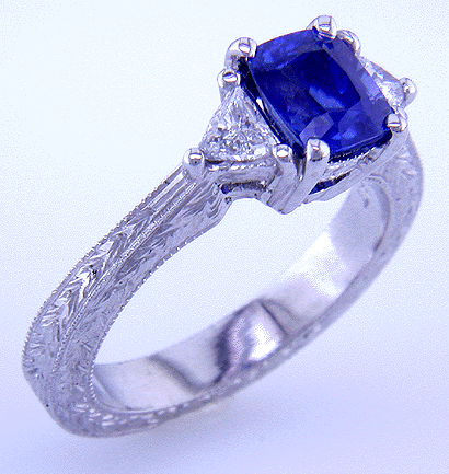 Hand engraved cushion sapphire and trilliant diamond ring in platinum.