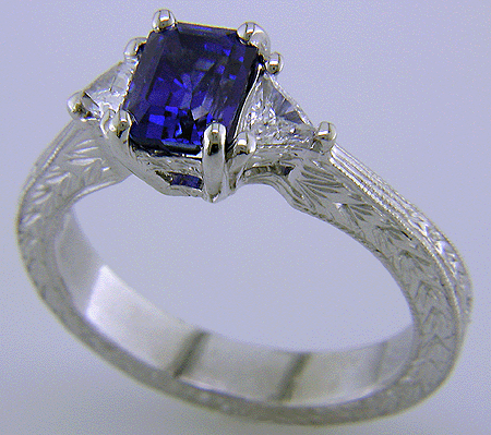 Hand engraved emerald-cut sapphire and trilliant diamond ring in platinum.