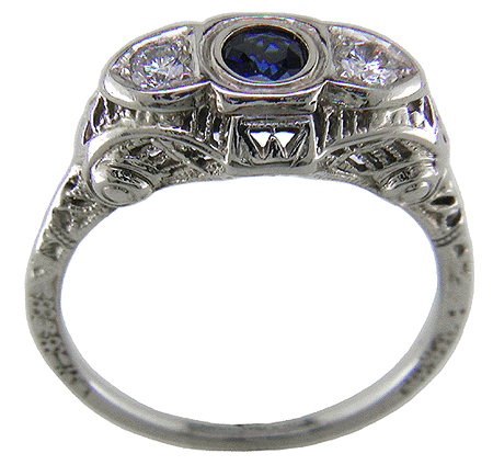 An antique filigree ring with a sapphire and two diamonds.