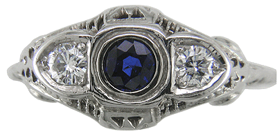 Top view of an antique filigree ring with a sapphire and two diamonds.