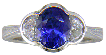 Oval sapphire set with crescent moon diamonds in an engraved platinum ring. (J7269)