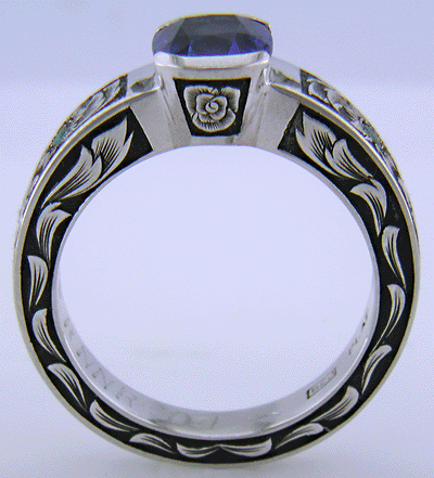 Side view of cushion-cut Sapphire set in a beautifully hand crafted and engraved platinum ring.