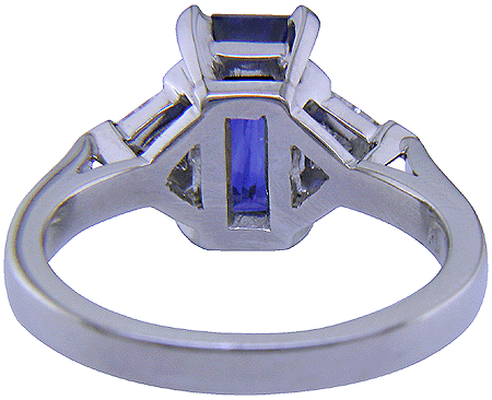 Inside view of handcrafted platinum ring with a sriking emerald-cut sapphire and two sparkling trilliant diamonds.