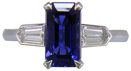 A handcrafted platinum ring with a sriking emerald-cut Sapphire and sparkling bullet-shape diamonds. (J7418)