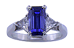 Hand-crafted emerald-cut sapphire ring with two sparkling trilliant diamonds.