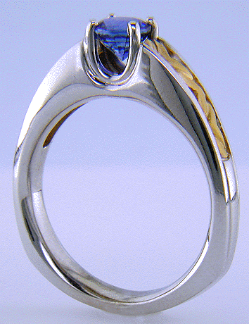 A blue sapphire set in an 18kt white gold ring with 22kt yellow gold shoulders.