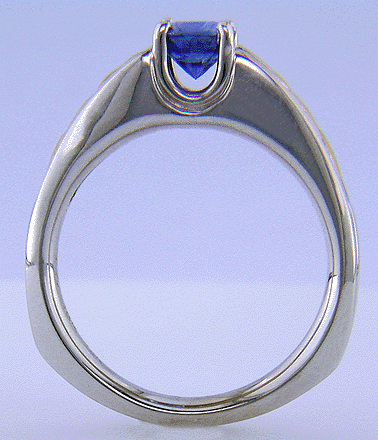 Side view of a blue sapphire set in an 18kt white gold ring with 22kt yellow gold shoulders.