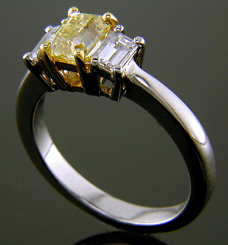 Fancy Yellow diamond with emerald-cut side diamonds in a platinum ring.