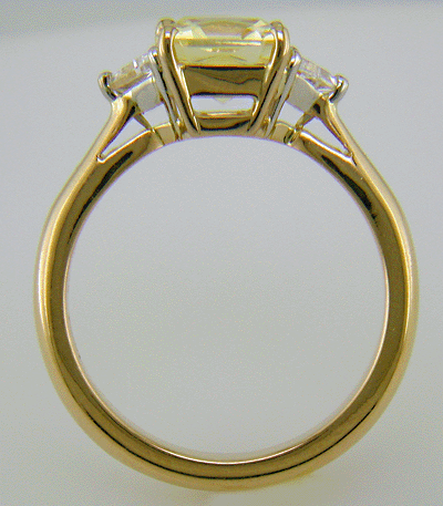 Side view of yellow sapphire set with two trilliant diamonds in a handcrafted 18kt gold and platinum ring.