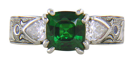 A cushion-cut Tsavorite garnet set in a beautifully hand crafted and engraved platinum ring.
