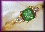 18kt gold ring with an emerald and princess cut diamonds.